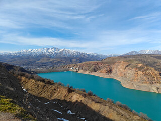 Scenic mountain landscape with turquoise lake and rocky cliffs under clear blue sky