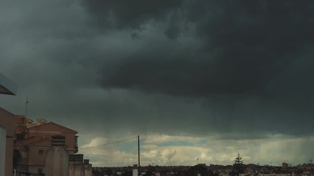 Dramatic weather transition unfolding, dark clouds dispersing over residential neighborhood, gradually revealing bright blue sky and transforming urban scenery.timelipse