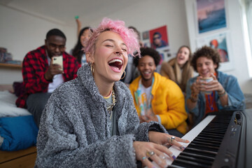 A joyful image of a woman with pink hair playing piano, surrounded by laughing friends. Captures the spirit of creativity, connection, and shared experience.