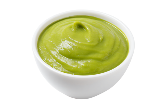 a bowl of green sauce on a white surface