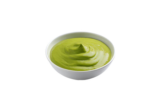 a bowl of green sauce on a white surface