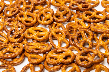 Background consisting of small traditional beer pretzels with salt isolated on white background