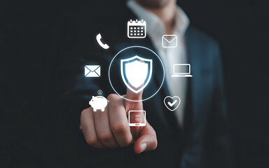 Business professional touching a glowing shield icon surrounded by digital security and data protection symbols