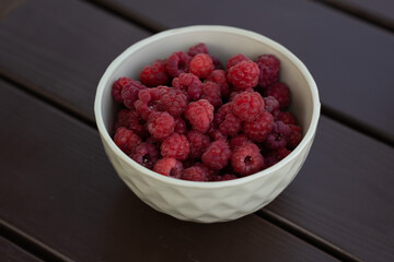 A bowl of fresh, juicy raspberries placed beautifully on a rustic wooden surface
