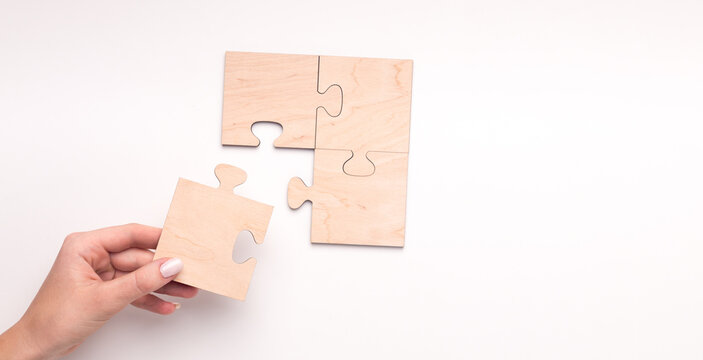 Woman creating wooden puzzle of four pieces with copy space for text on white background, panorama