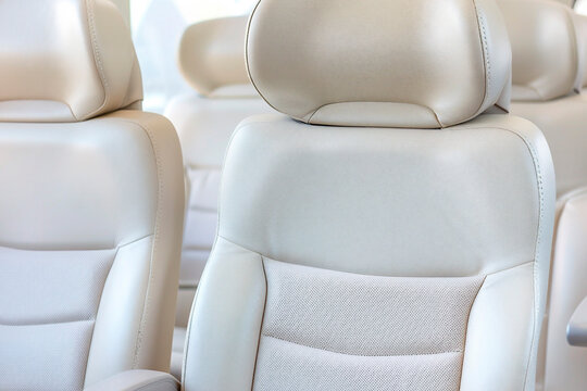 Close-up of luxurious beige leather bus seat with adjustable headrest and soft padding for passenger comfort during travel - Powered by Adobe