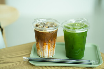 Close up glass of ice caramel macchiato and ice pure matcha green tea on green tray of a coffee shop summer terrace, menu photography.