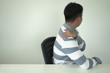 Man having tensed muscles fatigued, neck, shoulder, back, wrist and arm pain during work long time in office, due to fibromyalgia, rheumatism, scapular pain, office syndrome and ergonomic concept.
