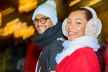 Happy couple smiling and enjoying christmas market at night