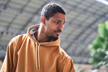 Young latino man wearing a hoodie looking down