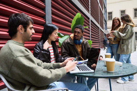 Young multiethnic professionals collaborating outdoors with technology