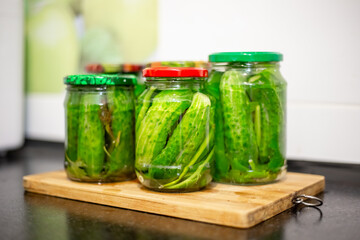 Jars of pickles arranged on wooden board, home canning process