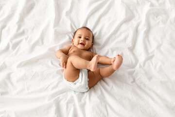 Nursery Concept. Top above view portrait of adorable small black baby wearing diaper lying on the...