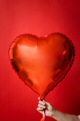 red heart in female hands on red background for valentines day