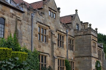 Historic stone building with tiled roof and ivy base; architectural grace softened by nature’s...