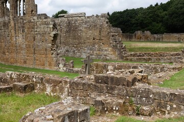 Stone ruins cascade across grassy terrain; fractured walls and shadowed recesses echo forgotten...