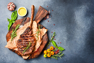 Beef steak on the bone. Grilled tomahawk steak with rosemary and spices on a cutting board. Top view. Free space for text.