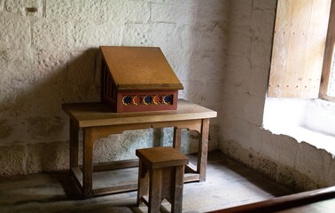 A small wooden desk and stool sit in front of a textured white wall in Mount Grace Priory - East Harlsey - North Yorkshire - UK