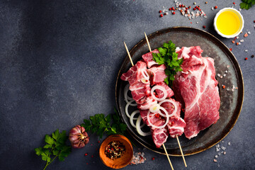 Raw pork neck cut into cubes in a bowl with onions and spices. Marinating kebab. On a gray stone...