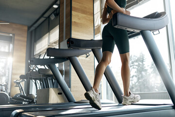 Woman running on treadmill in bright modern gym