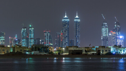 Obraz premium Modern Dubai city skyline timelapse at night with illuminated skyscrapers over water surface