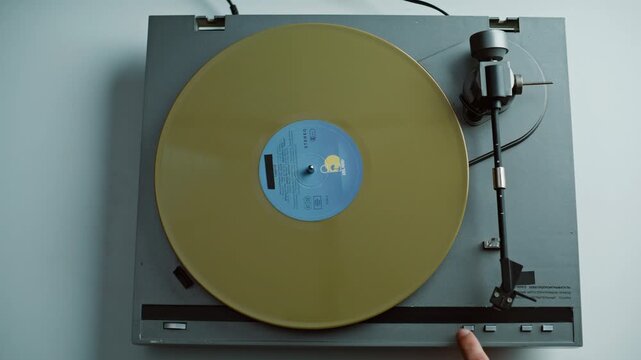 Man start vinyl play putting yellow disc on classic gramophone at home closeup. 