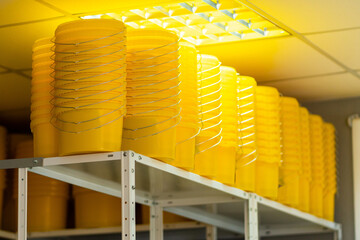 Many yellow color buckets cans in a row with ink paint row