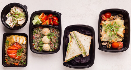 Healthy food in black delivery boxes for lunch in office on white background, panorama