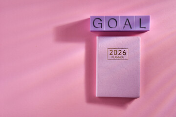 2026 planner and toy block with text GOAL against pink background.