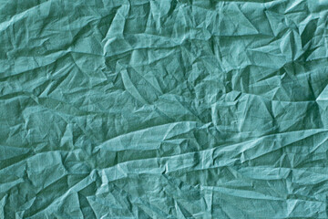 Textured fabric surface with crumpled folds in a solid green color