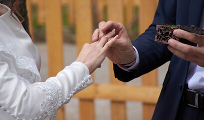Young couple at the wedding exchanges engagement rings