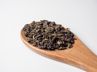 large wooden spoon on a white background. Green leaf tea is poured into a spoon. Tea party concept....