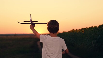 Boy plays aviator. Airplane pilot. Child dream of becoming astronaut. Kid, become pilot of plane. Happy boy runs with toy airplane at sunset. Child dreams of flying. Concept of child dream of flying
