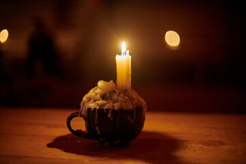 Single candle burns brightly on rustic wooden table in dimly lit room, creating warm, serene...