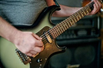 Close up of musician hands playing an electric bass guitar, focusing on precise finger placement...