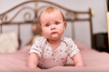 Young female child with light hair, playful expression, star-patterned pajamas. Pink bedding,...