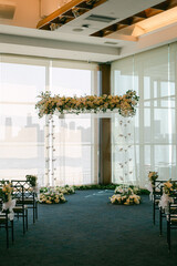 Elegant wedding ceremony setup with floral arch in a modern venue by the waterfront