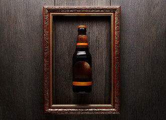 A bottle of dark beer within an ornate, gilded picture frame.