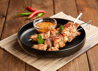 Grilled Satay Chicken Skewers with Peanut Sauce and Chilies in plate side view of Asian cuisine