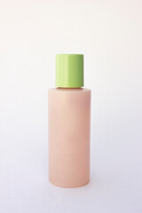 Pink facial cleanser bottle mockup with green cap isolated on bright background. 
