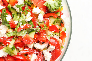 Fresh summer vegetable salad. Colorful mix of tomatoes cucumbers feta and herbs. Healthy vegetarian meal in glass bowl. Top view of vibrant homemade dish. Bright white background with empty copy space