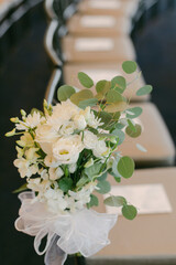 Elegant floral arrangement adorns seating at a wedding ceremony in a beautifully decorated venue
