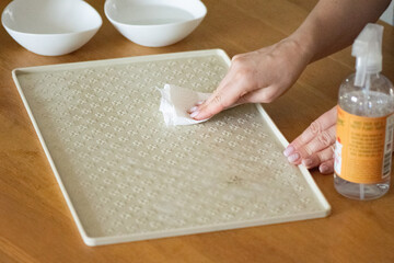 Cleaning a non-slip silicone food mat for cats with eco-friendly spray and paper towel