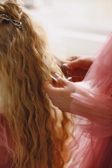 Close up photo of mom stroking her daughter's long wavy hair. Happy motherhood and childhood concept