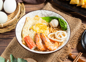 Delicious Seafood Noodle Bowl with Shrimp, Calamari, Crab Stick, Egg, and Greens in bowl side view...