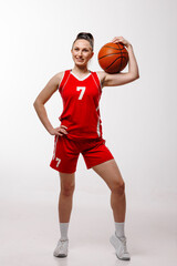 Naklejka premium Confident female basketball player in red uniform holding ball, sports portrait on white background