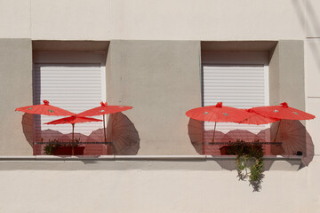 facade with two identical windows and three red umbrellas on each window