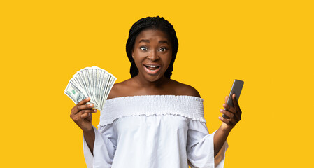 Fast Credits. Excited Black Lady Holding Smartphone And Dollar Cash, Got Easy Loan, Received...