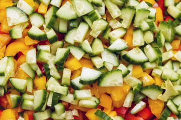 Fresh vegetable salad closeup. Chopped cucumber, yellow and red bell peppers. Summer healthy food background. Colorful raw ingredients in natural light. Bright clean texture for healthy eating design.
