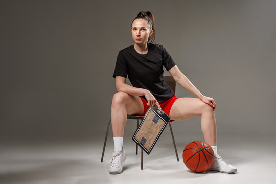 Female basketball coach or player with tactics board in studio, modern women’s sports leadership